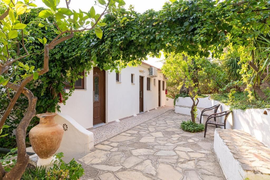 A stone-paved courtyard with white walls, a wooden door, and a bench.