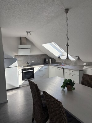 Una cocina moderna con armarios blancos, horno integrado y tragaluz.
