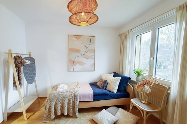 Une chambre confortable avec un lit, une table de chevet, une chaise, un luminaire suspendu et une fenêtre donnant sur un beau paysage.