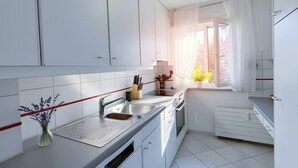 Eine moderne Küche mit weißen Schränken, einer Edelstahlspüle und einem Fenster mit Vorhängen.