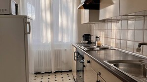 Cocina compacta con refrigerador, horno y lavamanos.