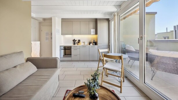Uma sala de estar moderna com sofá, mesa de centro e área de jantar com cadeiras.