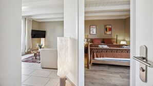 Quarto de hotel com cama, escrivaninha, cadeira, televisão e janela com cortinas.