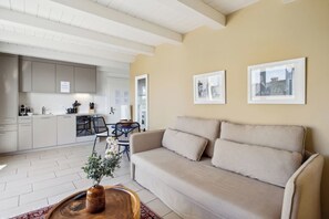 A modern living room with a beige sofa, a wooden coffee table with a vase, and a dining area with a black chair and table. - Comfortable Flat with Terrace in Zurich (401-16) (Zürich)