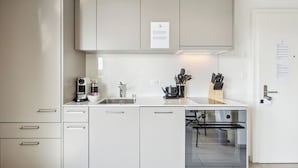 A modern kitchen with white cabinets, a coffee machine, a sink, and a dishwasher. - Comfortable Flat with Terrace in Zurich (401-16) (Zürich)