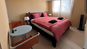 Ein Hotelzimmer mit einem Bett, einem kleinen Tisch mit Stuhl, einer Lampe und einem Heizgerät.