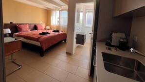 Ein Hotelzimmer mit Bett, Nachttisch und einer Küchenzeile.