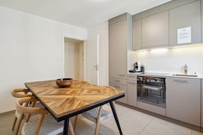 Una cocina moderna con una mesa de comedor de madera, sillas y un horno empotrado.