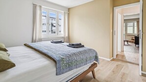 Une chambre à coucher avec un lit, une fenêtre, un ventilateur de plafond et une vue sur l’extérieur.