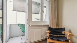 Une pièce avec une chaise en bois, un radiateur et une fenêtre avec des rideaux.