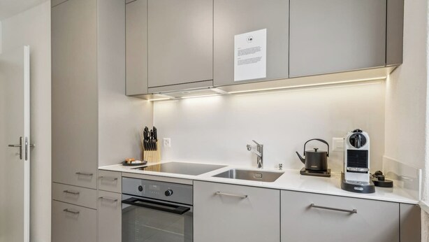 Une cuisine moderne équipée d’appareils électroménagers en acier inoxydable, d’un évier à deux bacs et d’un four encastré.