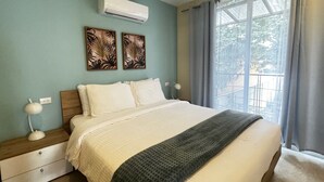 A bedroom with a bed, two wall-mounted air conditioners, a window with curtains, and two wall-mounted lamps. - Nangu Apartment in Coco (Coco)