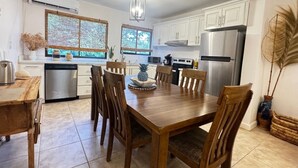 Une cuisine moderne avec des armoires blanches, des appareils en acier inoxydable et une table à manger en bois.