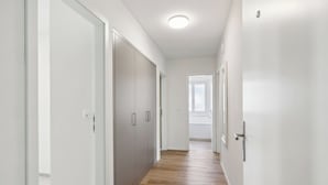 A hallway with white walls, wooden flooring, and a ceiling light. - Elegant City Apartment with Balcony! (101-16) (Zürich)