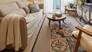 A cozy living room with a sofa, coffee table, and a TV on a stand. - Elegant City Apartment with Balcony! (101-16) (Zürich)