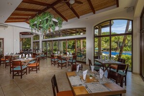 A restaurant with multiple dining tables, chairs, and hanging plants. - Modern & Scenic Haven | Breathtaking Views - Pool (Coco)