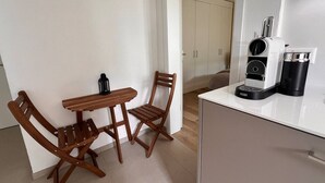 Een kleine kitchenette met een koffiezetapparaat, een tafel en twee stoelen.