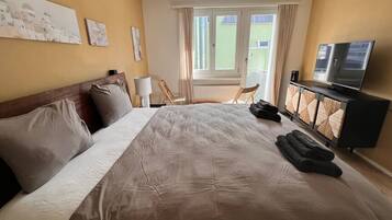 A hotel room with a large bed, a television, and a view of the outside.