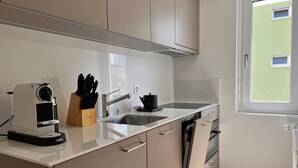 Een moderne keuken met een inbouwoven, een koffieapparaat en een messenblok.