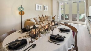 Un coin repas avec une table ronde dressée pour quatre personnes, entourée de chaises en bois.