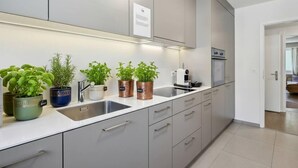 Une cuisine moderne avec des meubles gris, un évier en acier inoxydable et des plantes en pot sur le plan de travail.