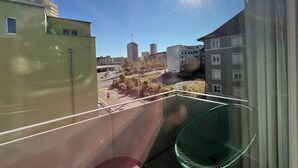 Un balcón con vistas a un paisaje urbano, que incluye edificios y un cielo despejado.