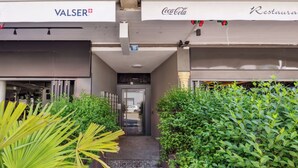 A commercial building with a VALSER sign, a Coca-Cola sign, and a restaurant sign. - Studio w/ Balcony & Modern Amenities (202-16) (Zürich)