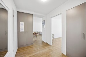 Un couloir avec un plancher en bois, un coin repas avec une table et des chaises, et une grande armoire avec une porte.