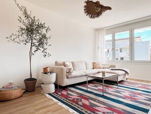 Una sala moderna con un sofá, una mesa de centro y una planta grande en maceta.