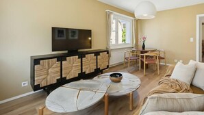 A modern living room with a flat-screen TV, a round coffee table, and a sofa.