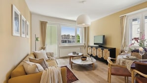 A living room with a sofa, coffee table, and dining area with chairs.
