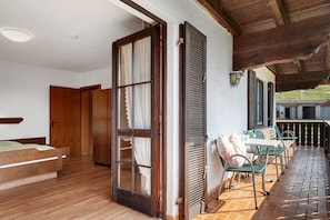 A bedroom with a wooden bed, a sliding glass door, and a balcony with outdoor seating. - Apartment 4 with Terrace, Barbecue Area and Wi-Fi (Oberharmersbach)