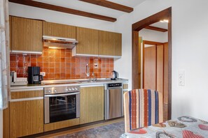 A kitchen with wooden cabinets, a stainless steel oven, a dishwasher, and a coffee maker. - Apartment 4 with Terrace, Barbecue Area and Wi-Fi (Oberharmersbach)