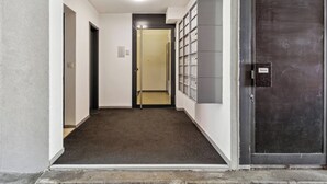 Un couloir doté d’un sol recouvert de moquette, une porte au fond et un meuble de rangement fixé au mur, muni d’une étiquette.