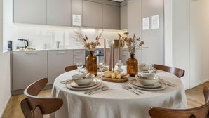 Un espace repas moderne avec une table ronde pour quatre personnes, entourée de chaises en bois.