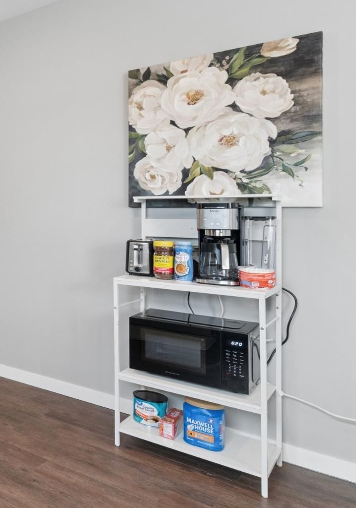 A kitchen area with a microwave, toaster, coffee maker, and storage shelves.