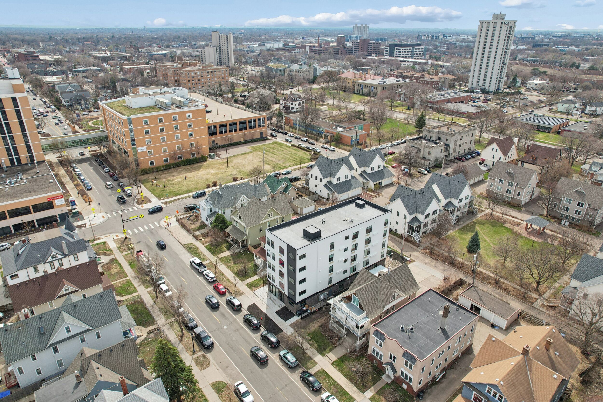 Une vue aérienne d’un quartier résidentiel comprenant un mélange de maisons unifamiliales et d’immeubles d’appartements, de routes et d’un grand bâtiment doté d’un toit végétalisé.
