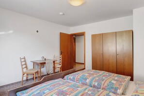 A bedroom with a bed, a wooden wardrobe, a desk with a chair, and a mirror. - Apartment 5 with Balcony, Barbecue Area and Wi-Fi (Oberharmersbach)