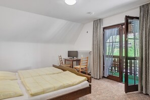 A bedroom with two beds, a desk with a computer, and a view of a garden through a sliding door. - Apartment 5 with Balcony, Barbecue Area and Wi-Fi (Oberharmersbach)