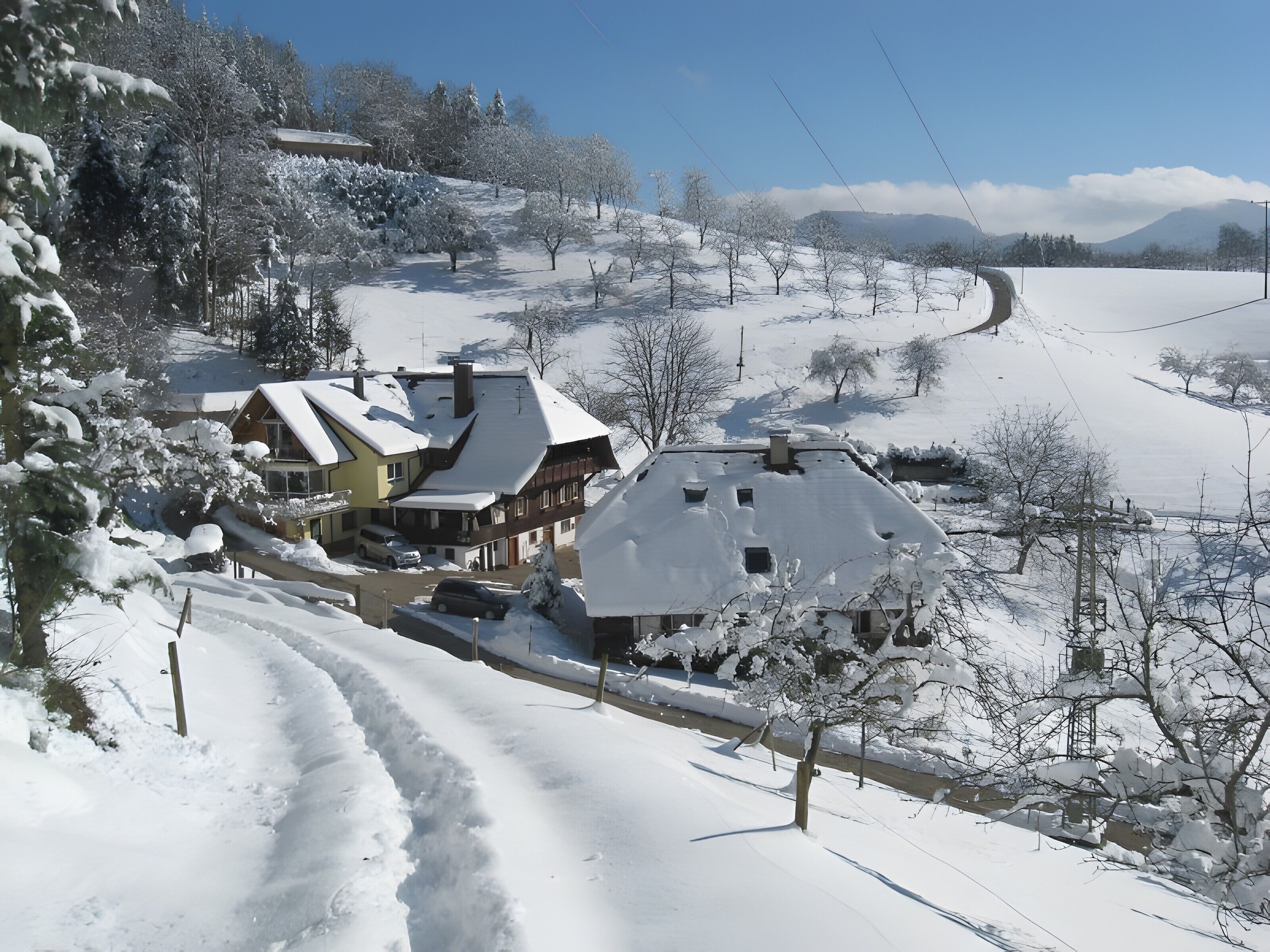 A snow-covered village with traditional houses, a winding road, and a clear sky.
