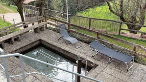 Un espace piscine doté d’une terrasse en bois, d’un escalier métallique pour accéder à la piscine et de deux chaises longues.