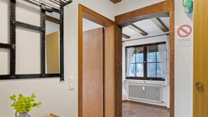Un couloir avec une porte en bois, un radiateur et une fenêtre avec des rideaux.