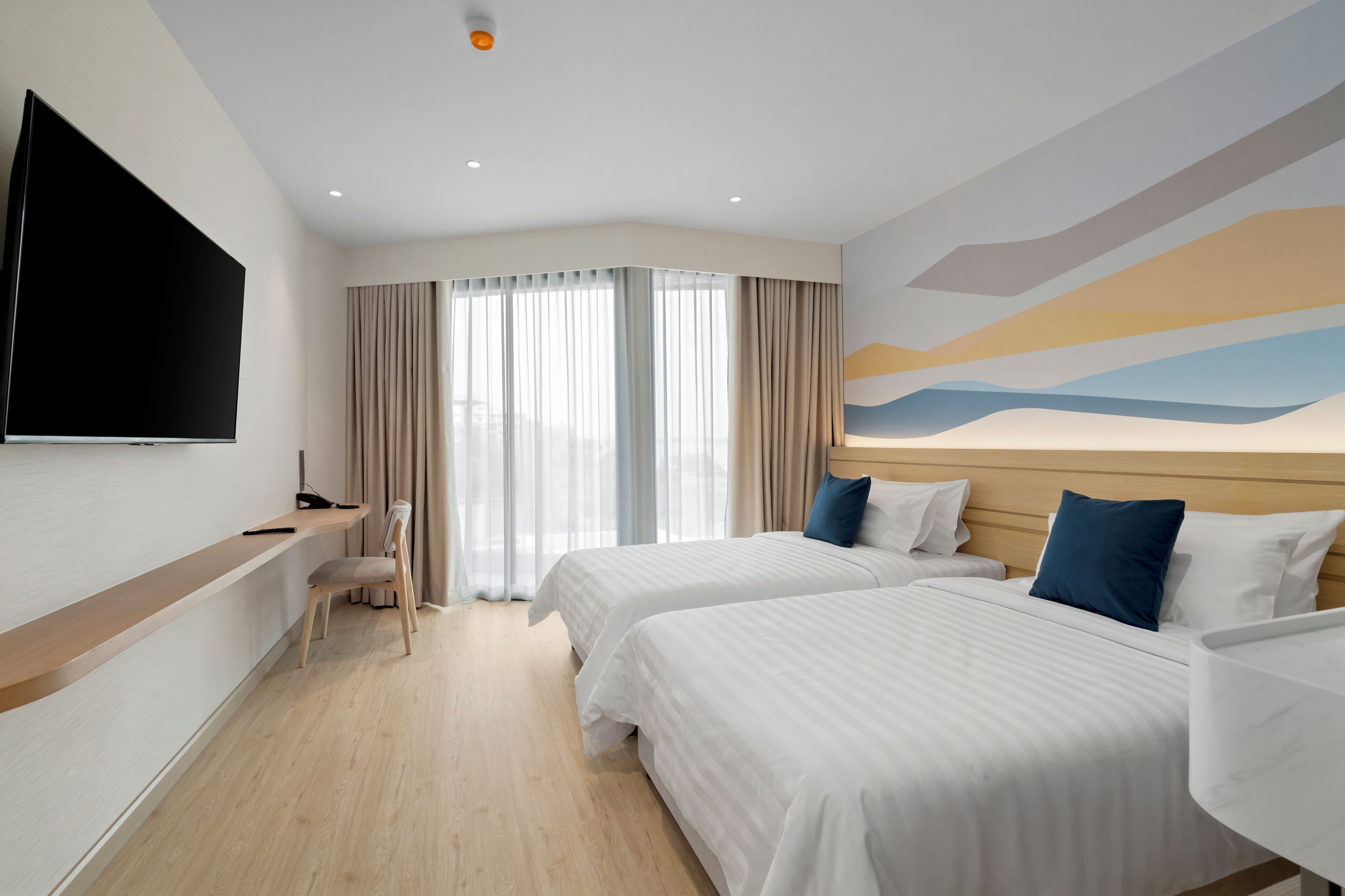 A hotel room with two beds, a TV, a desk, and a chair.