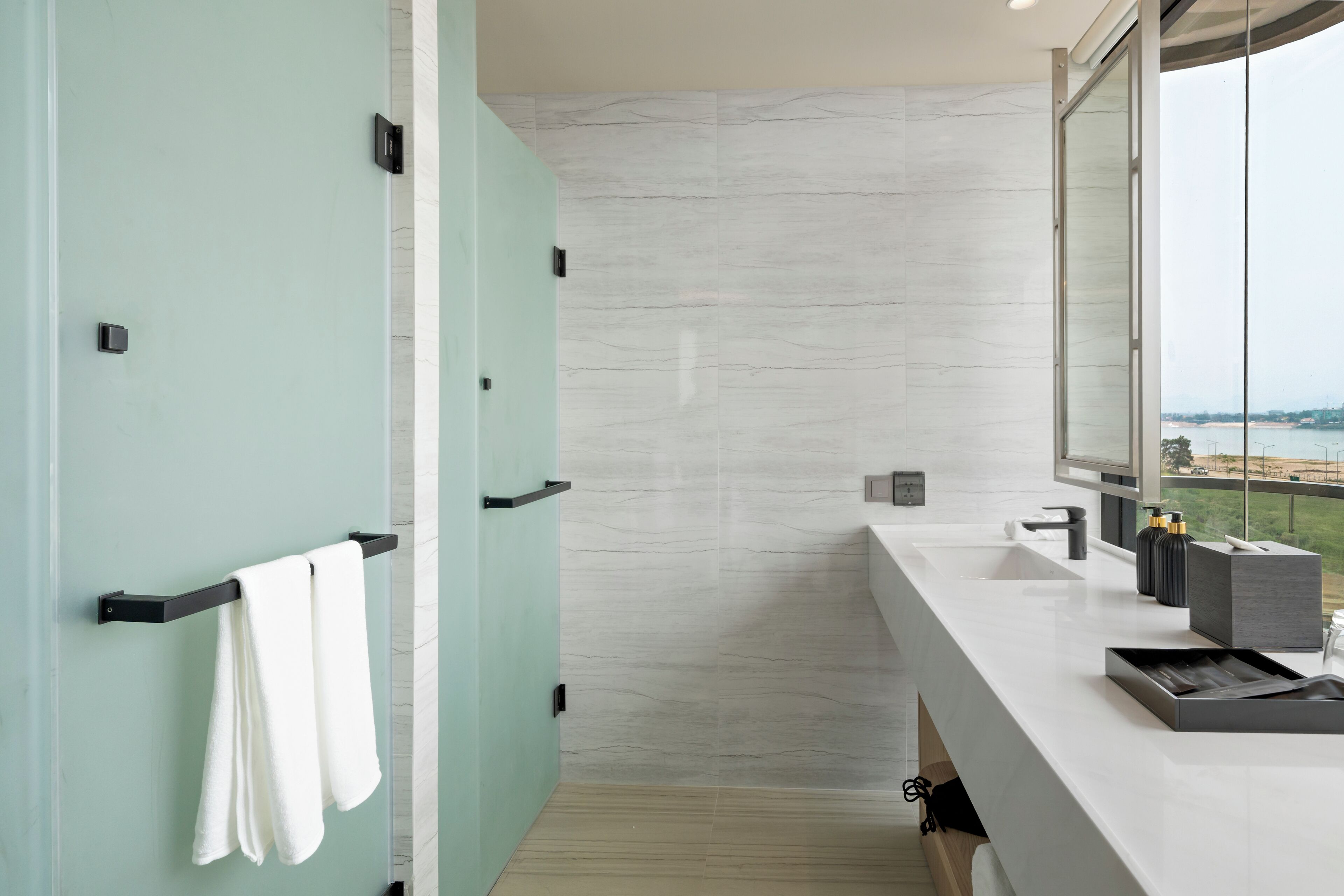 Un baño moderno con un espejo grande, zona de ducha y tocador con lavabo y encimera.
