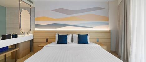 Camera d'albergo con un letto grande, un comodino, uno specchio, un'opera d'arte appesa al muro e una finestra con tende.