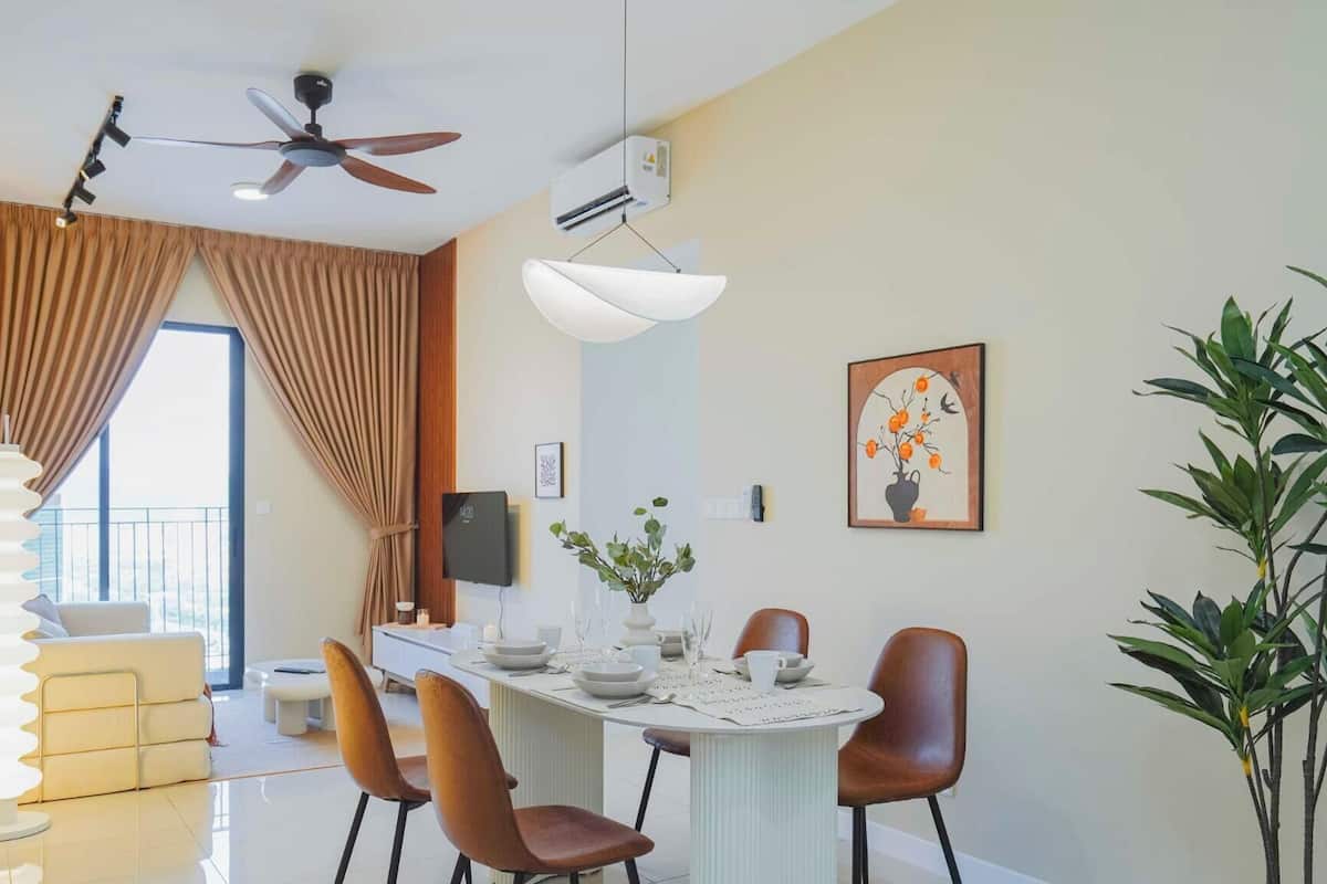 Een eethoek met een tafel gedekt voor vier personen, een plafondventilator, een airconditioning en een groot raam met gordijnen.