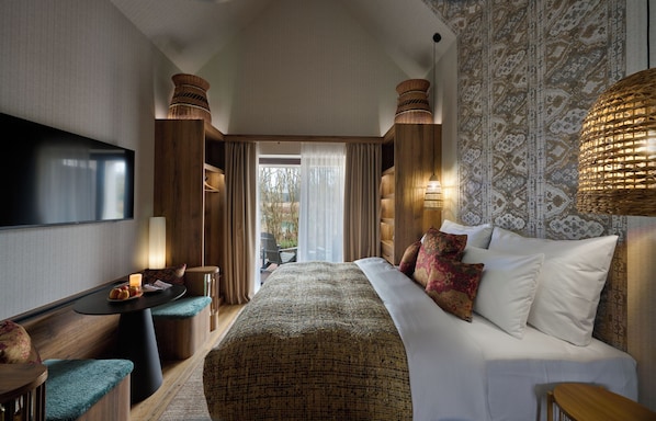 Een hotelkamer met een groot bed, een televisie, een klein tafeltje met fruit en uitzicht op de omgeving.