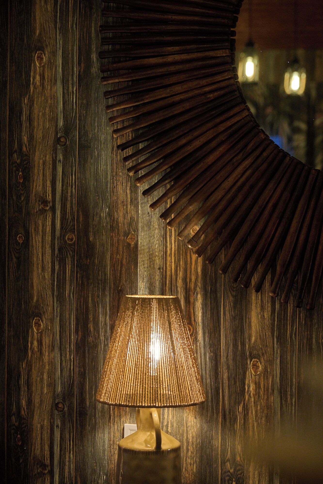 A wooden wall with a circular mirror and a lamp.