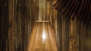 A wooden wall with a circular mirror and a lamp.