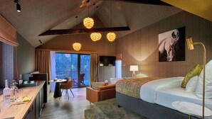 A modern hotel room with a large bed, a desk, and a dining area.